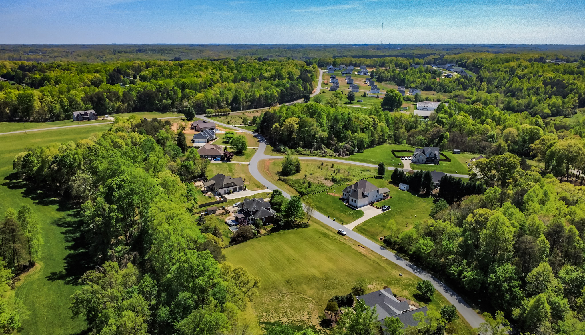 A sweeping aerial view of homes surrounded by green woodland